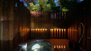 A wooden spa area with a hot tub, wooden deck, and a wooden fence. - Ryokan Wataya (Karatsu)
