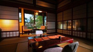 A traditional Japanese room with tatami flooring, a low table, and sliding doors. - Ryokan Wataya (Karatsu)