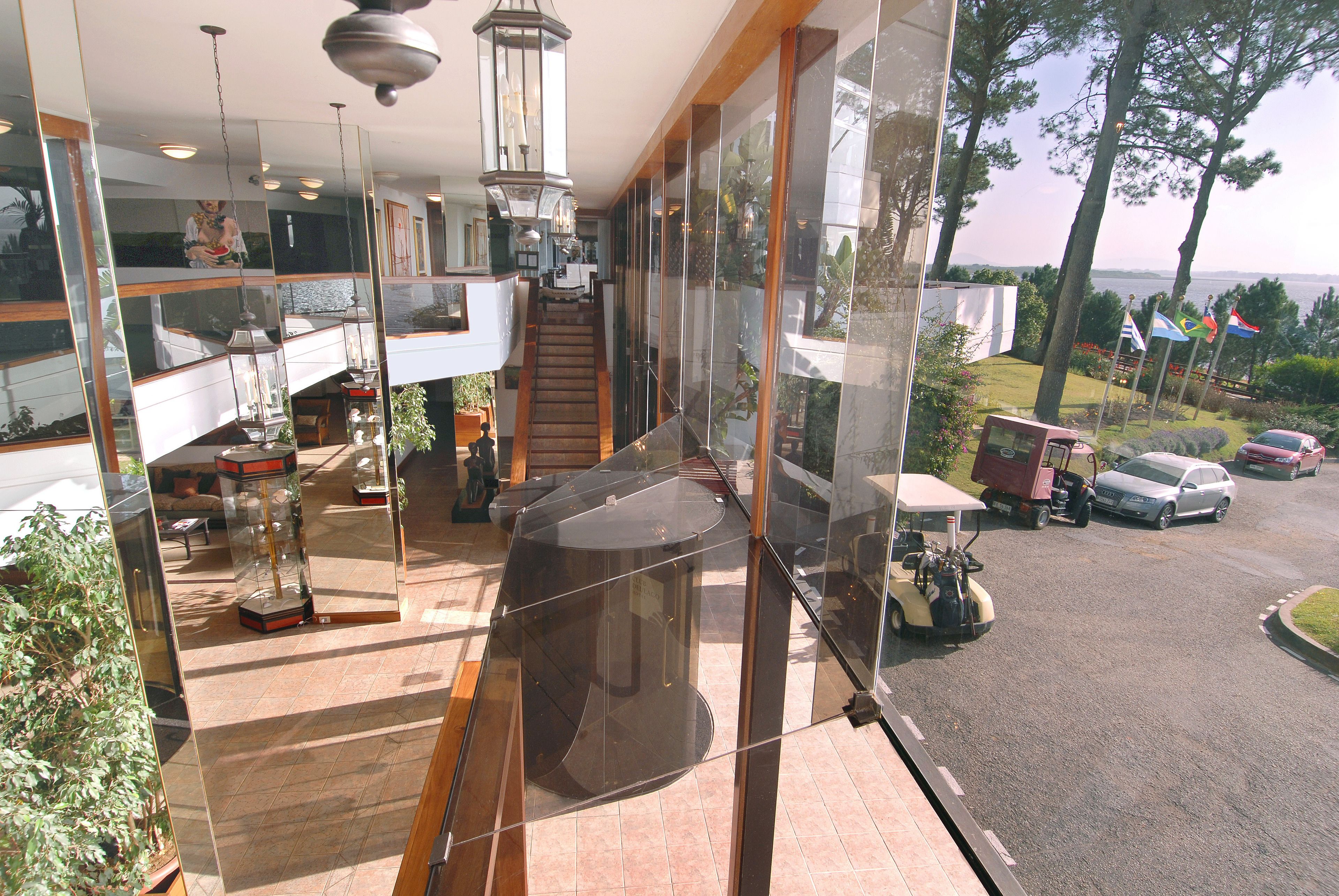 A modern interior with a glass wall overlooking a parking area and a view of the sea.
