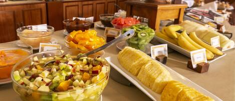 A buffet with various fruits and a fruit salad bowl.