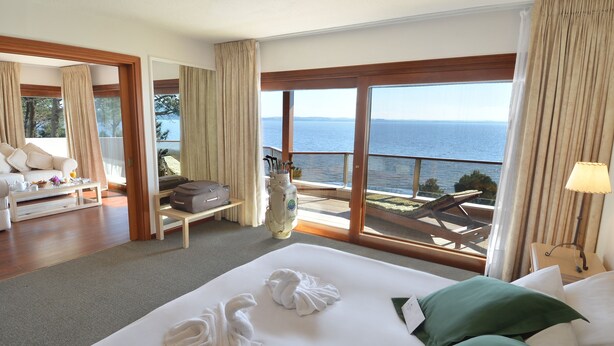 Een hotelkamer met een groot bed, een slaapbank, een salontafel en uitzicht op zee.