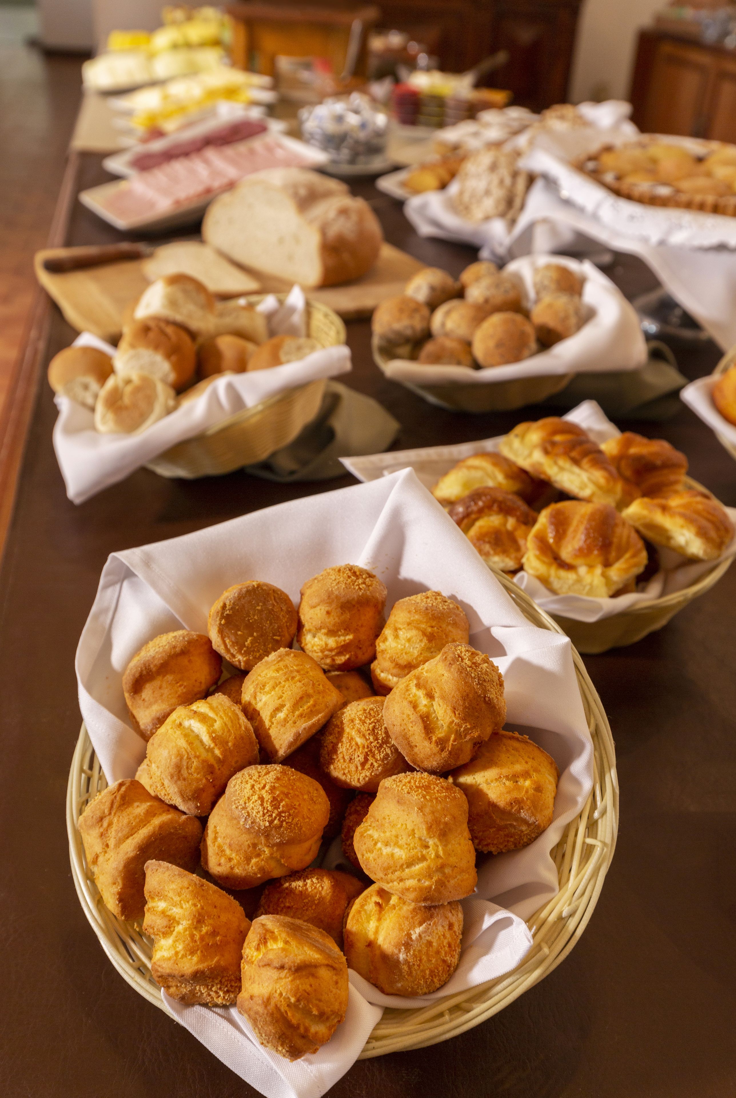 A buffet table with various baked goods, including bread, pastries, and rolls.