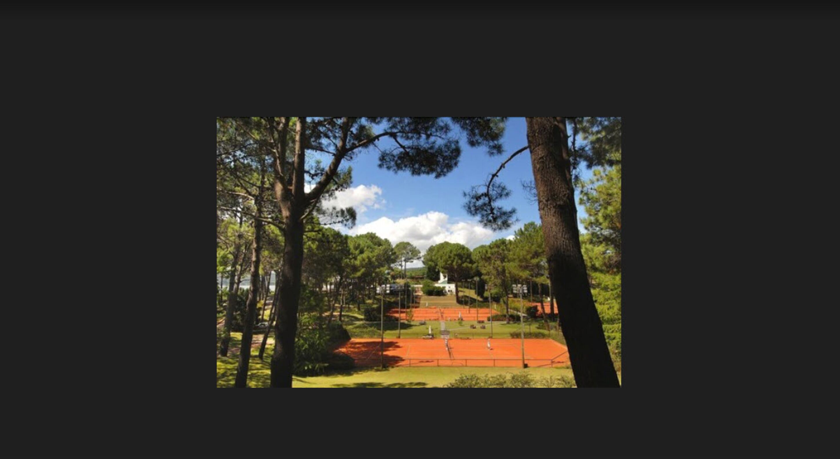 A tennis court surrounded by trees and a building in the background.