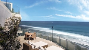 A balcony with a view of the ocean, furnished with wicker furniture and a table. - C151 Dreamland (Pecatu)