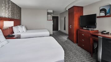 A hotel room with two beds, a desk, a television, and a wardrobe.