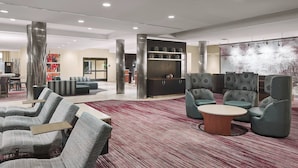 A modern lobby with seating areas, a reception desk, and a large abstract painting on the wall. - Courtyard by Marriott Shreveport-Bossier/Louisiana Boardwalk (Bossier City)