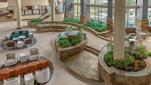 A spacious lobby with a central fountain, seating areas, and a view of the outdoors through large windows. - Embassy Suites San Antonio Riverwalk-Downtown (San Antonio)