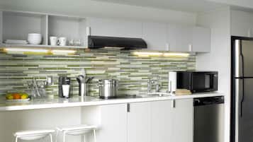 Una cocina moderna con armarios blancos, un refrigerador de acero inoxidable, un microondas y un salpicadero de azulejos.