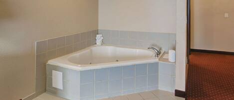 A bathroom with a white bathtub, light blue tiles, and a red patterned carpet.