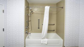 Ein modernes Badezimmer mit Badewanne, Dusche und Haltegriffen.