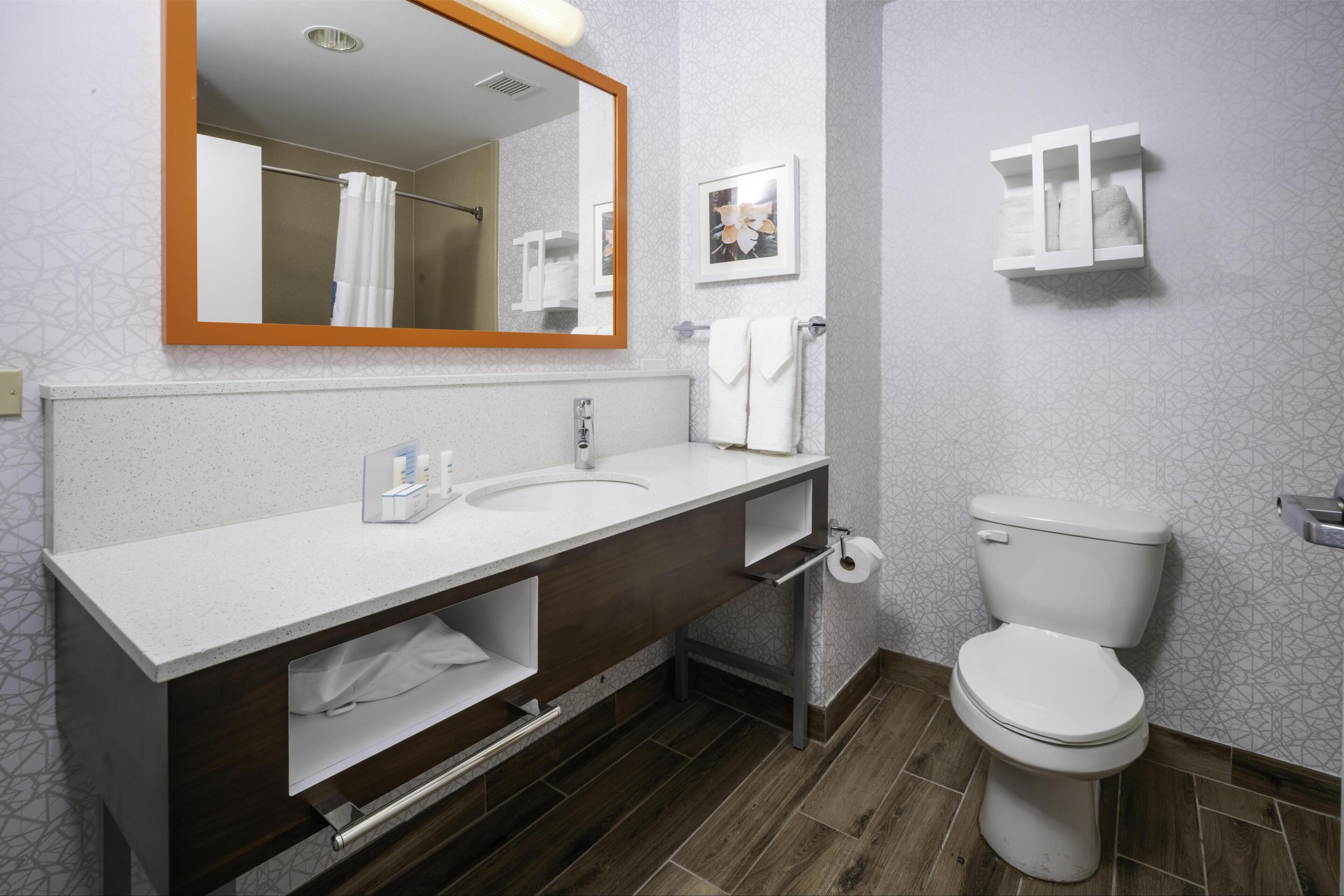 Un bagno con doppio lavandino, un water, uno specchio e un porta asciugamani.