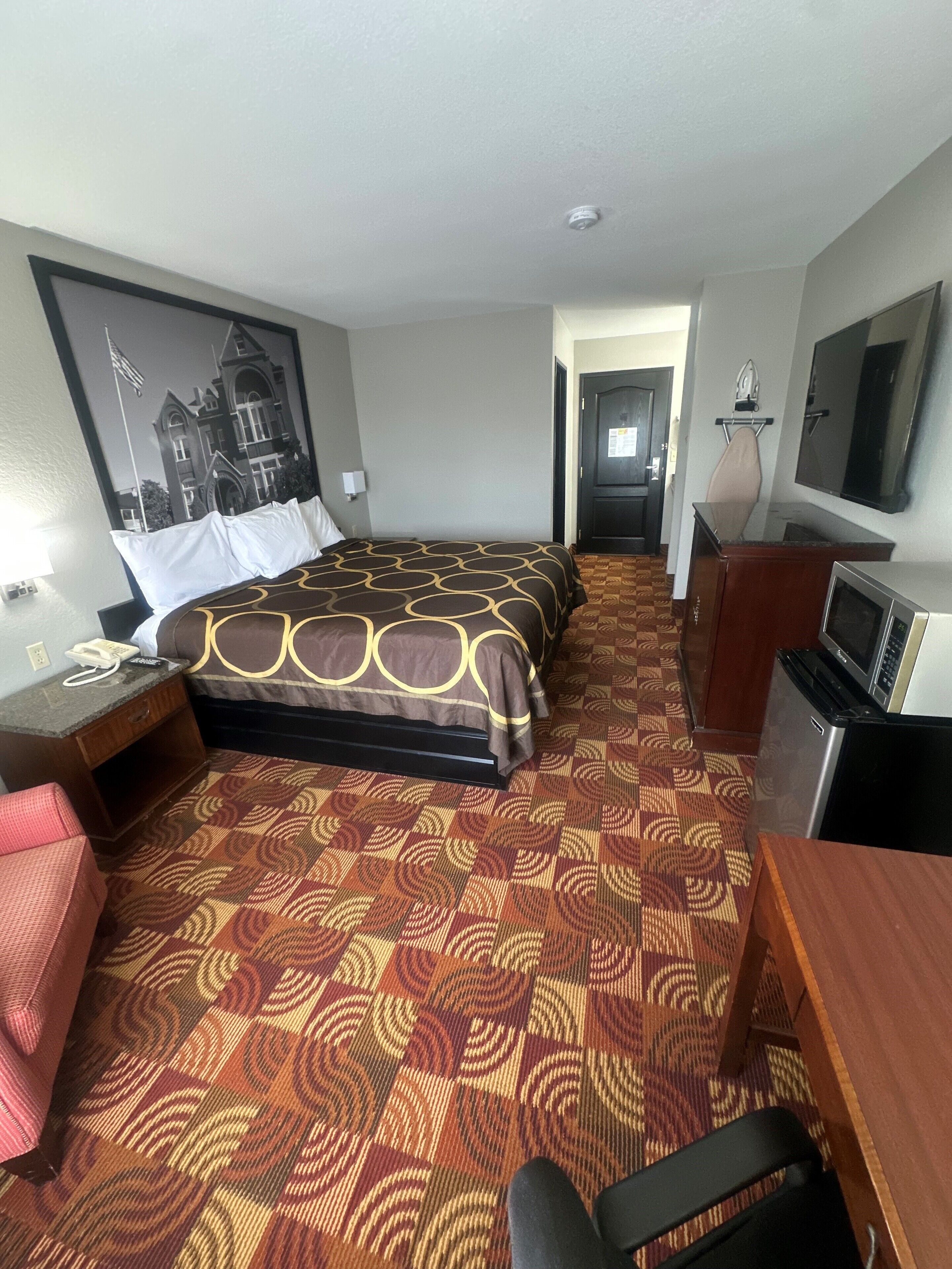 Een hotelkamer met een groot bed, een bureau, een stoel, een televisie en een magnetron.