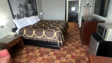 Een hotelkamer met een groot bed, een bureau, een stoel, een televisie en een magnetron.
