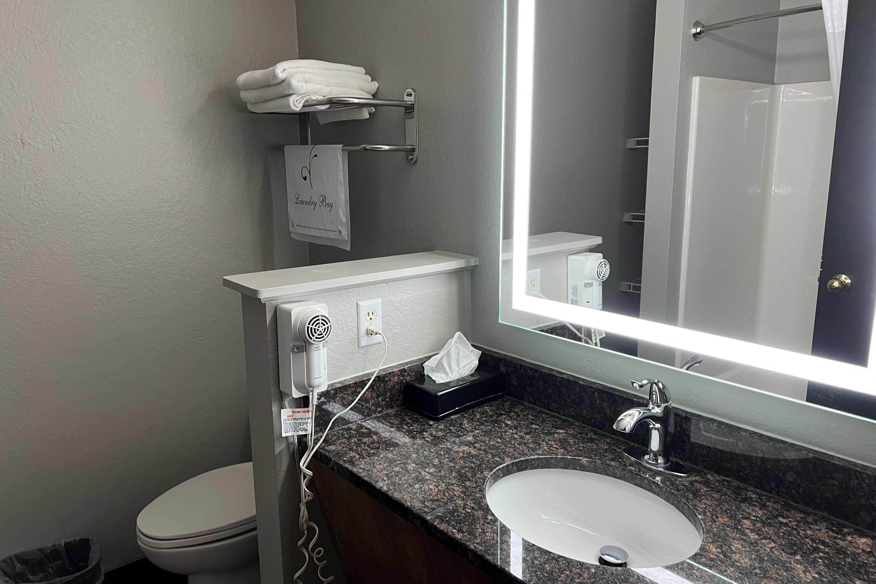 A bathroom with a toilet, a sink, a mirror, and a towel rack with folded towels.