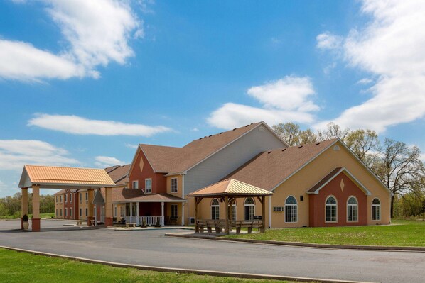 A large, multi-story building with a covered entrance area, multiple windows, and a parking lot. - Super 8 by Wyndham Lake of the Ozarks (Eldon)