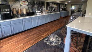 Un área de cocina moderna con barra desayunadora, mostrador con dispensadores y una estación de café.