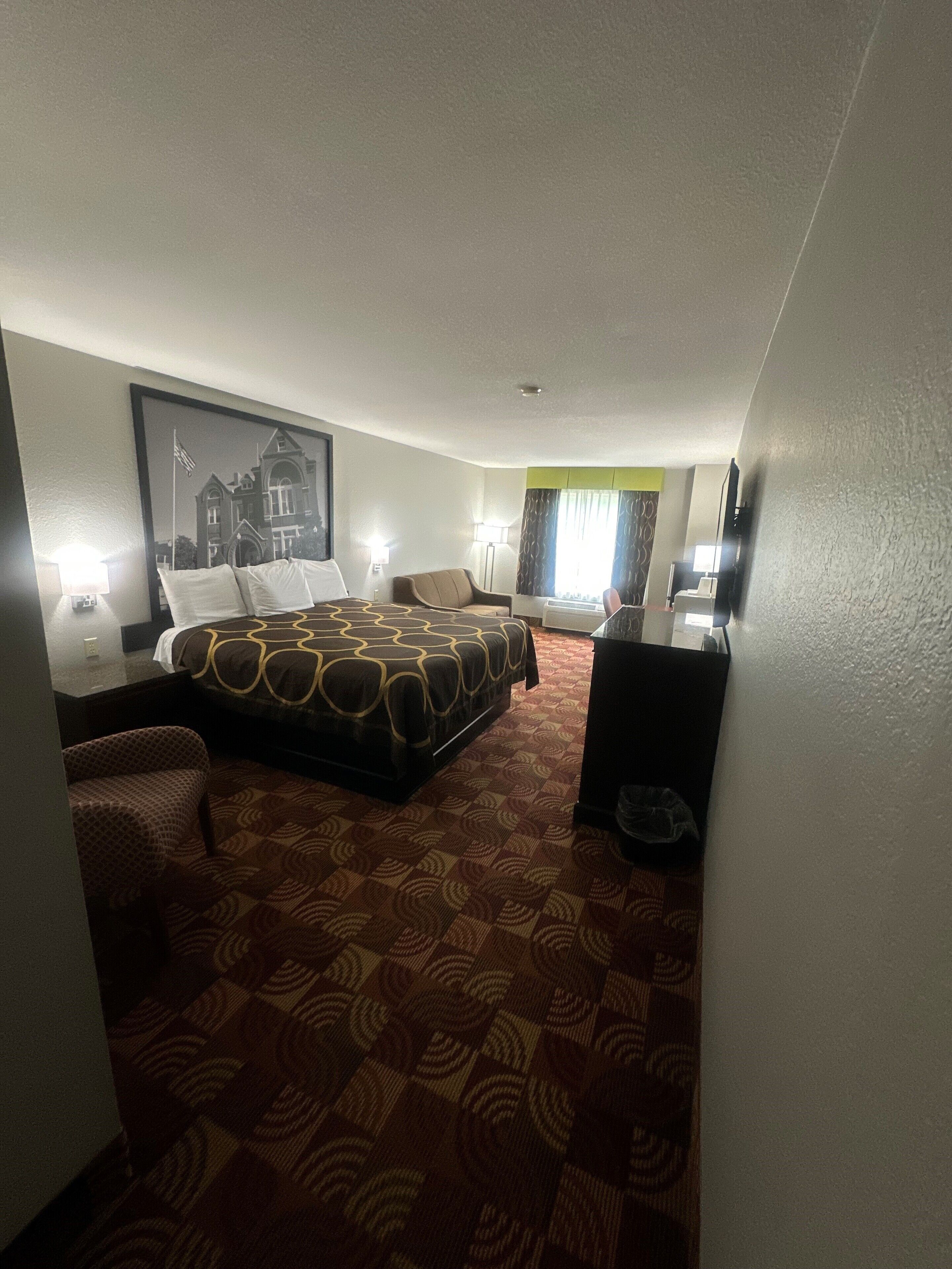 A hotel room with a large bed, a sofa, a desk, and a TV.
