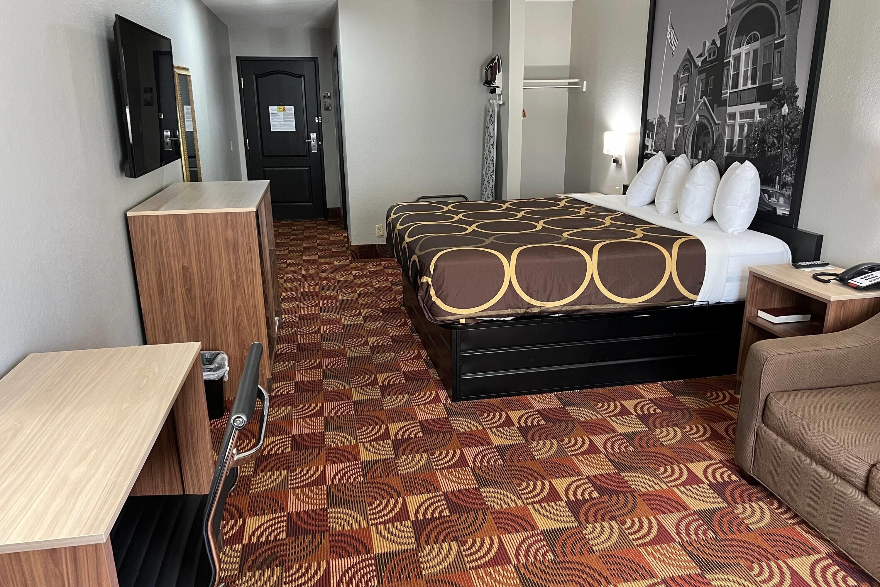 A hotel room with a bed, a desk, a chair, a wardrobe, and a bathroom.