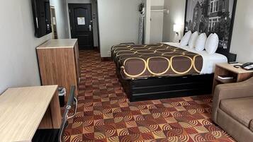 A hotel room with a bed, a desk, a chair, a wardrobe, and a bathroom.