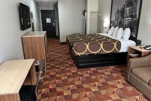 A hotel room with a bed, a desk, a chair, a wardrobe, and a bathroom.