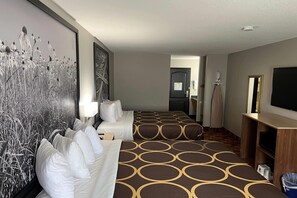 A hotel room with a large bed, a TV, a desk, and a painting on the wall. - Super 8 by Wyndham Lake of the Ozarks (Eldon)