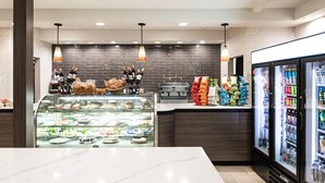 Un'area moderna dedicata al cibo, con un banco gastronomia, vetrine refrigerate e lampade pendenti.