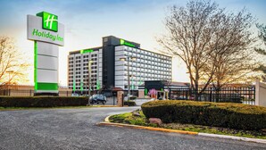 Un hotel Holiday Inn con un cartello ben visibile, un parcheggio e un paesaggio curato.