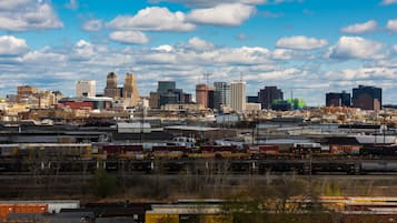 A city skyline with various buildings, including a prominent clock tower, under a partly cloudy sky.