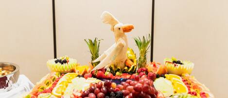 A fruit platter with a bird decoration, surrounded by tropical fruits and berries.