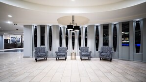 Una hall moderna con soffitto curvo, illuminazione a incasso e poltrone sagomate disposte a semicerchio.
