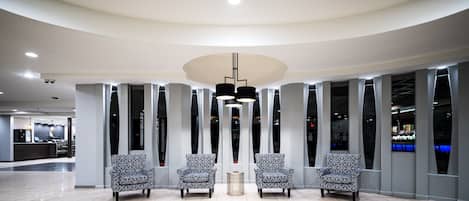 A modern lobby with a curved ceiling, recessed lighting, and patterned chairs arranged in a semi-circle.