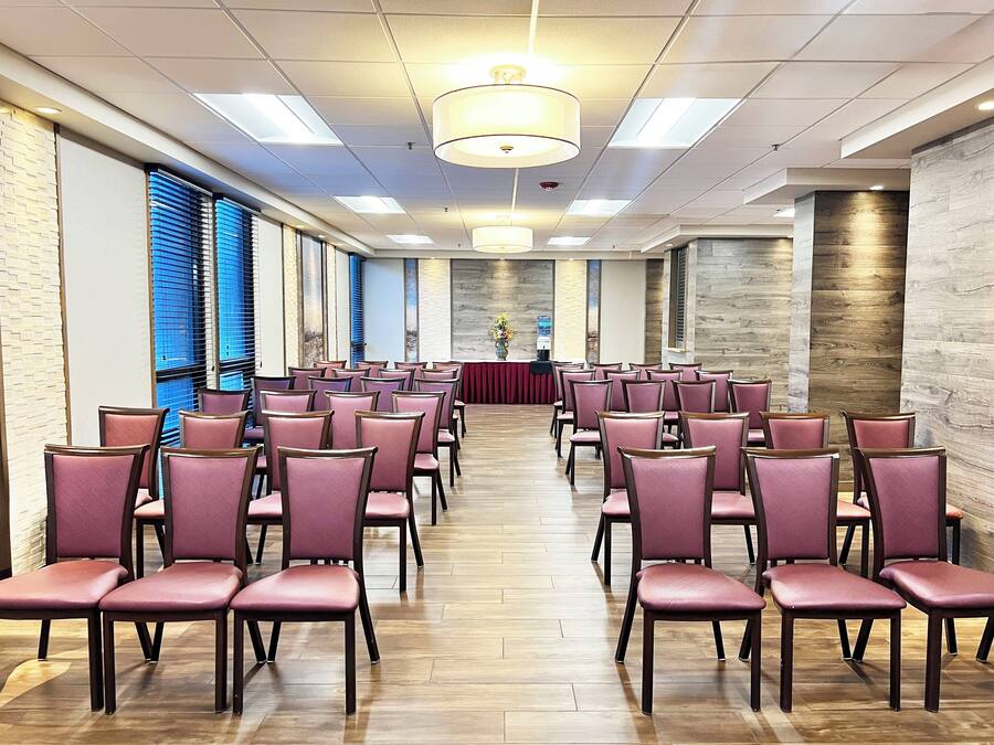 A conference room with rows of chairs, a stage with a red backdrop, and a water dispenser.