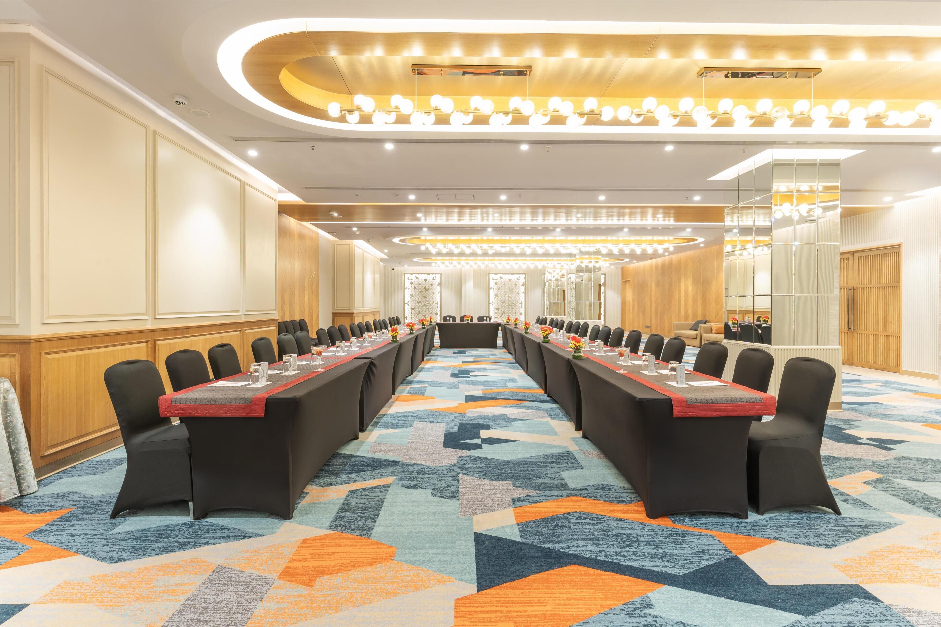 A conference room with a long table, black chairs, and a patterned carpet.
