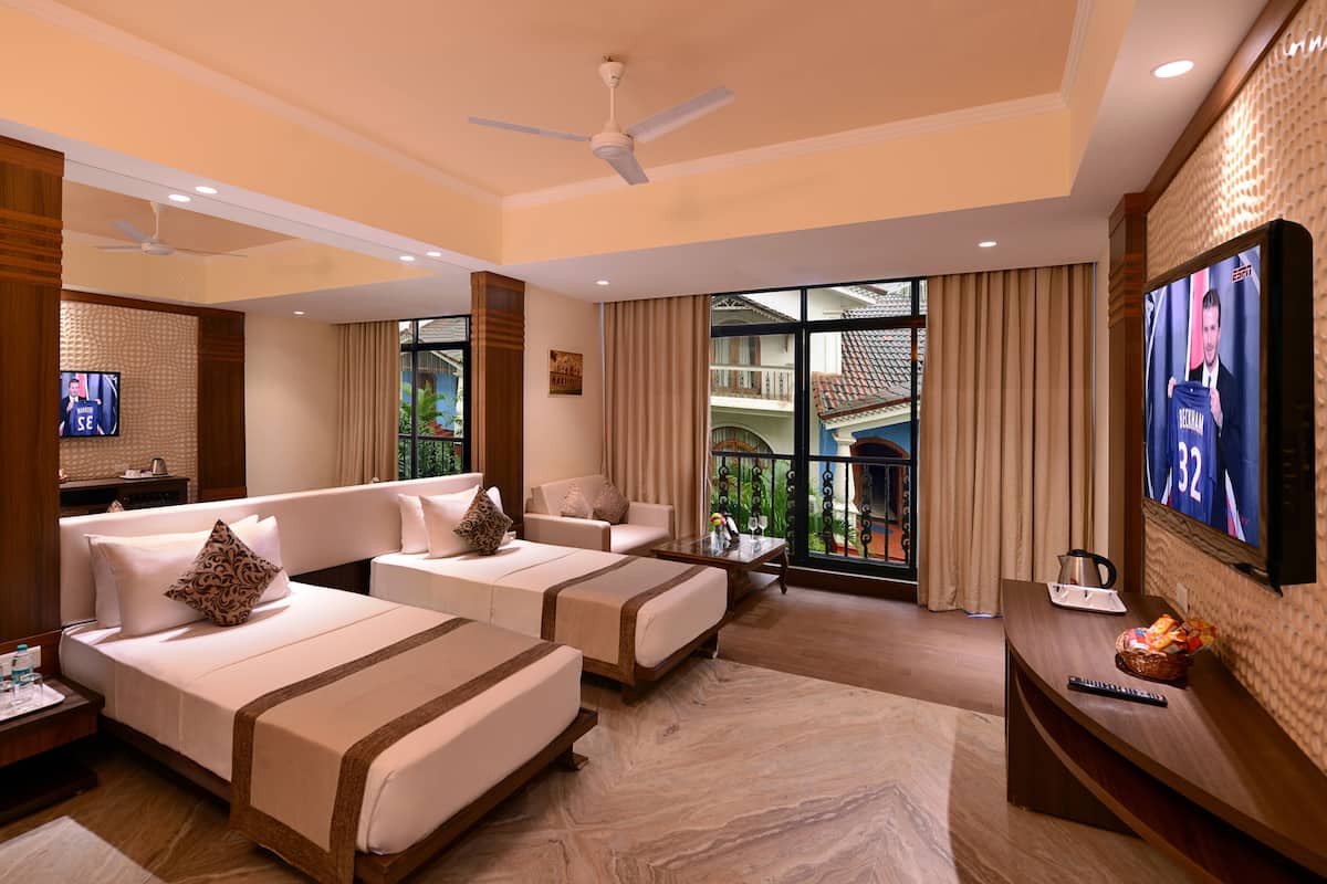 A hotel room with two beds, a TV, a balcony with a view, and a ceiling fan.