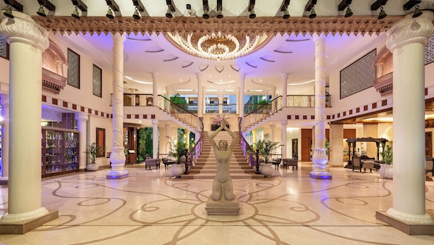 A grand lobby with a central statue, multiple floors, and a chandelier.