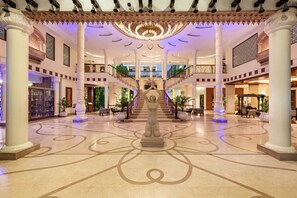 A grand lobby with a central statue, multiple floors, and a chandelier. - Resort Rio (Arpora)