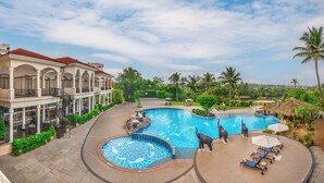 A resort with a large swimming pool, palm trees, and a building with a red roof.