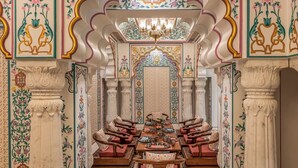 A traditional interior with ornate floral patterns, a central chandelier, and seating arrangements.
