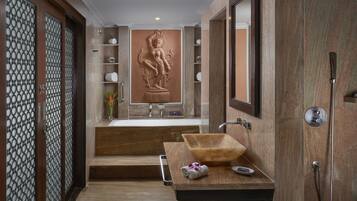 Un baño moderno con tocador de madera, un espejo grande y una escultura decorativa en la pared.