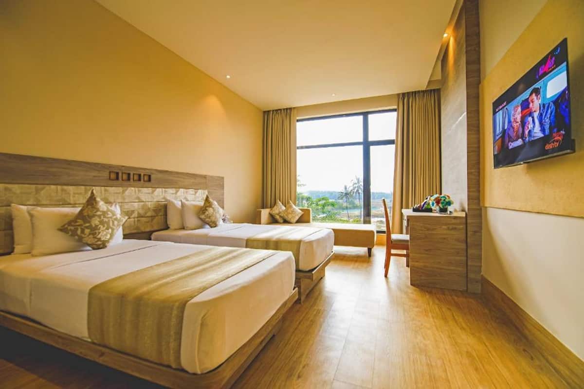 A hotel room with two beds, a desk, a TV, and a large window with a view.
