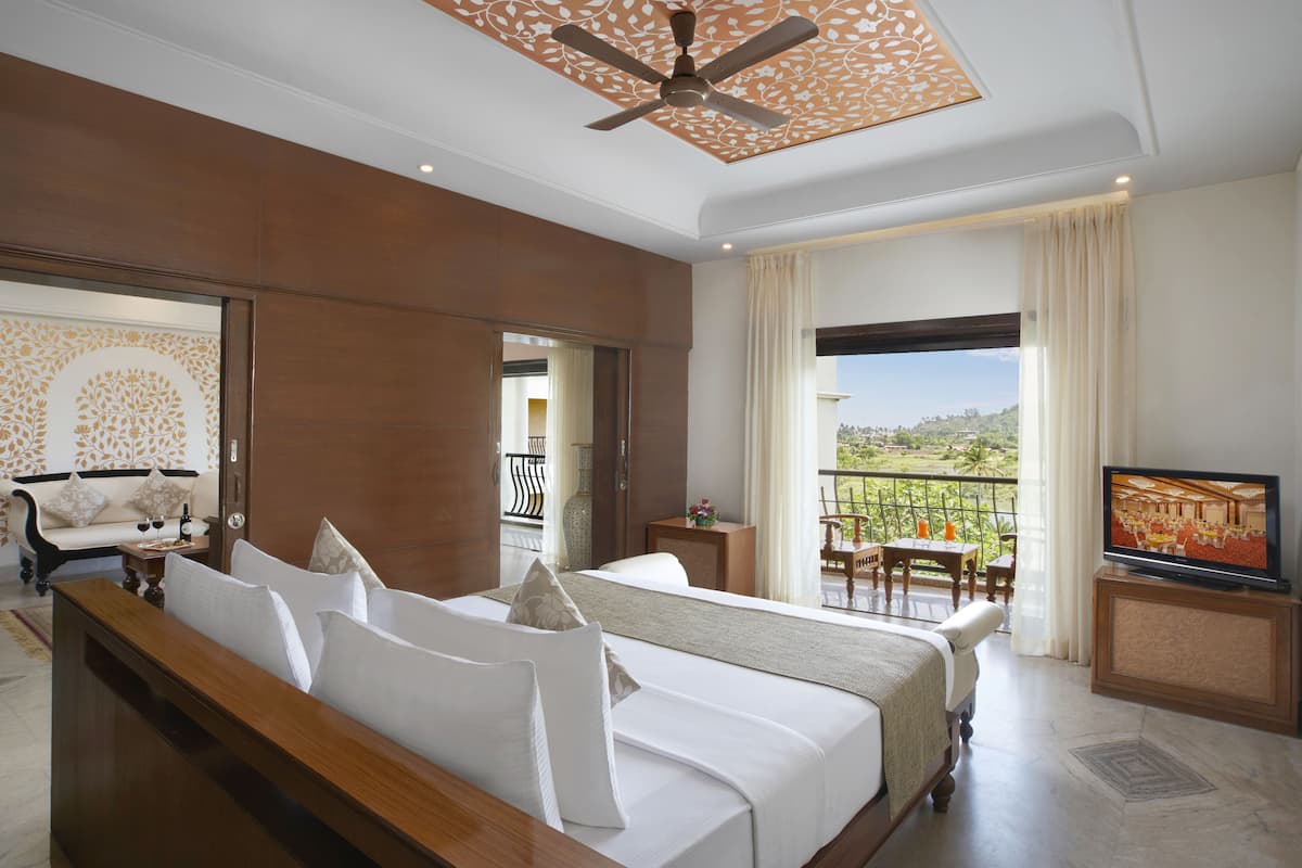 A hotel room with a bed, a television, a balcony with a view, and a dining area.