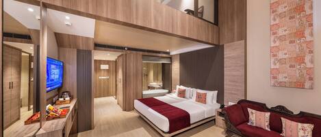 A modern hotel room with a large bed, a sofa, a TV, and a dining area.