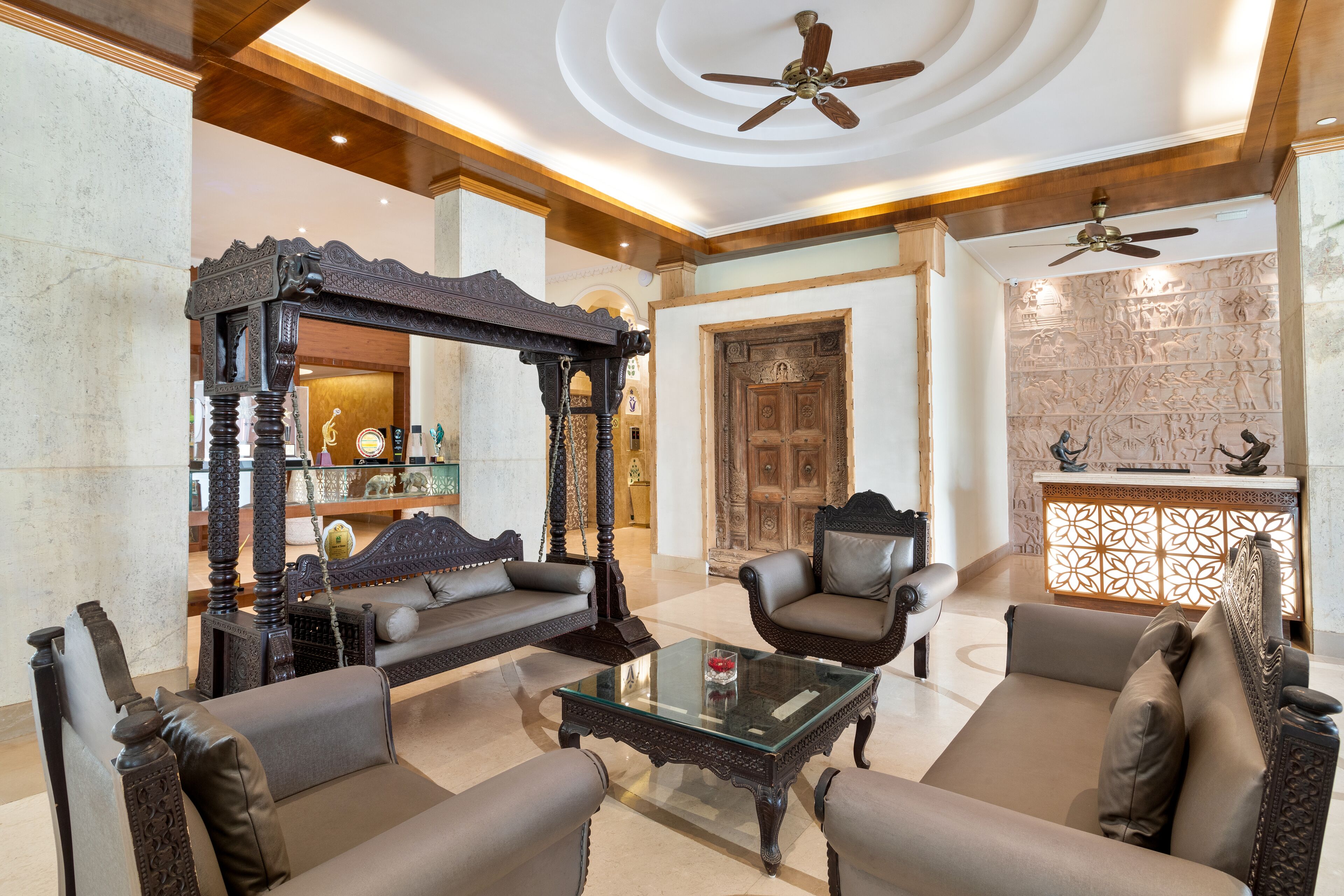 A lobby with a four-poster bed, leather sofas, a glass coffee table, and a reception desk with a decorative screen.