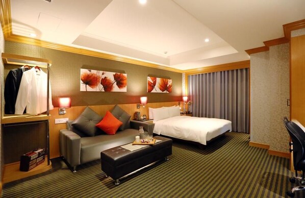 A hotel room with a bed, a sofa, a coffee table, and a desk.