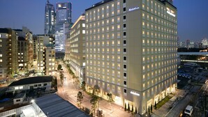 Un hotel de varios pisos con fachada uniforme, numerosas ventanas y una entrada central.