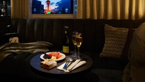A cozy room with a view of a lit tower, a dining table with a bottle of wine, glasses, and a plate of food. - Mitsui Garden Hotel Shiodome Italia-gai Tokyo (Tokyo)
