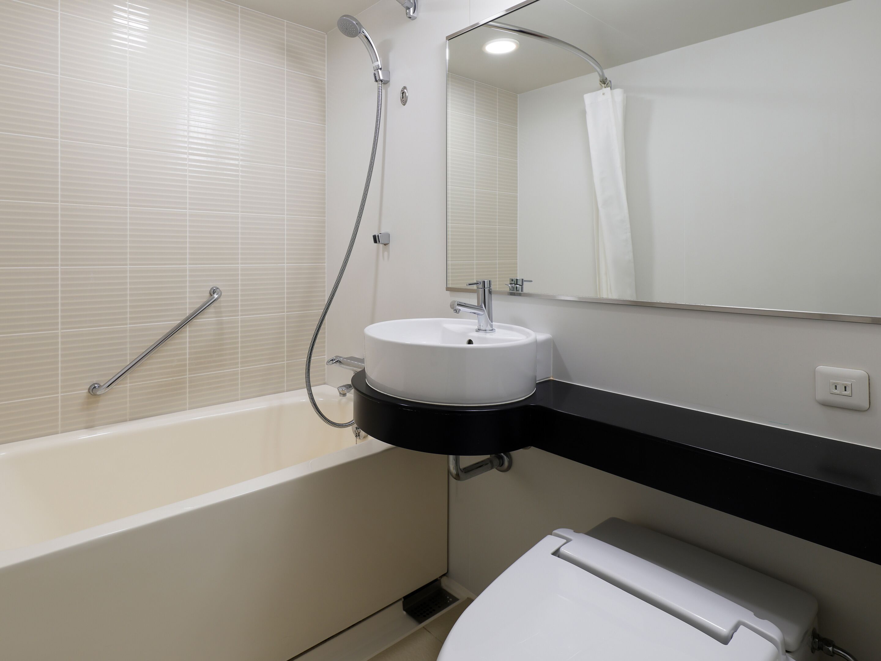 A modern bathroom with a bathtub, a sink, a toilet, and a shower.