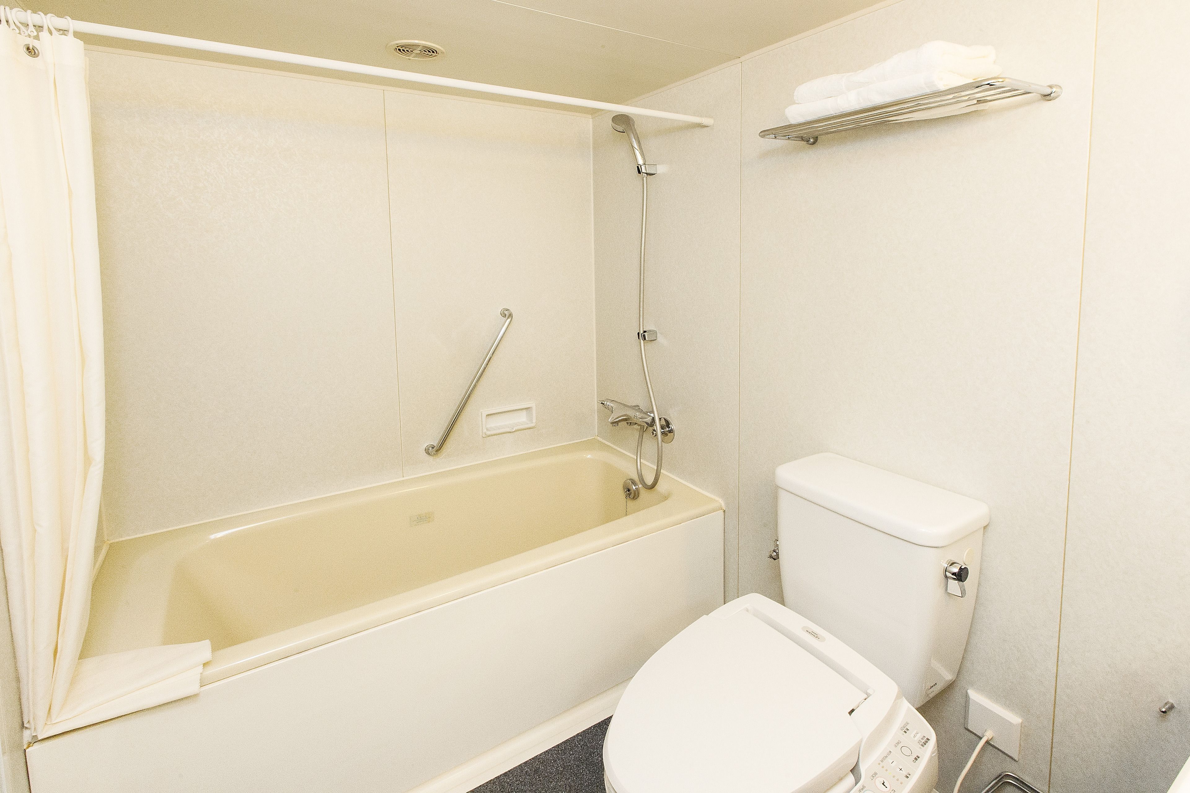 Un ba ño con bañera, inodoro y un perchero para toallas.
