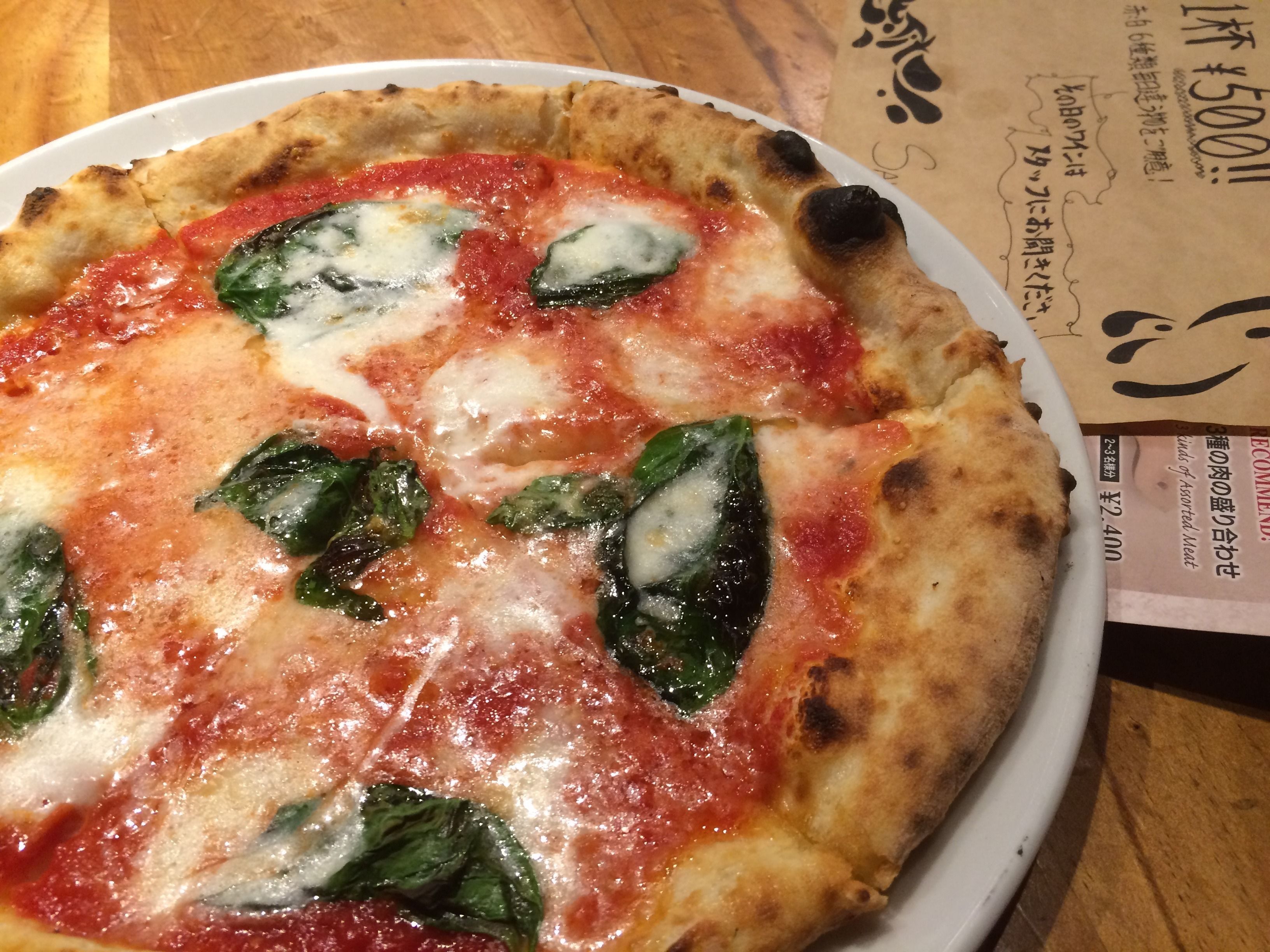 A pizza with spinach and cheese on a white plate.