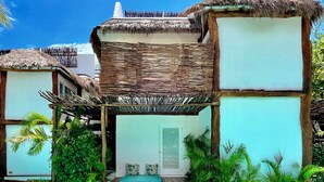 Un complejo turístico con construcciones de techo de paja, piscina y exuberante follaje.